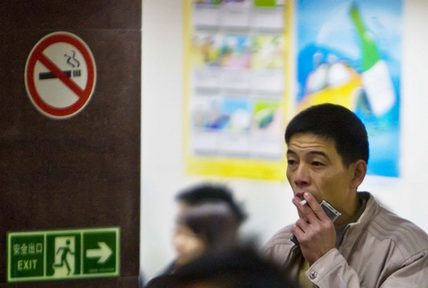 A man ignores a nearby no-smoking sign in the waiting hall of Foshan Bus Station in Foshan, South China's Guangdong province. Provided to China Daily Tobacco scientist uproar flares
