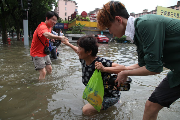Residents form a chain as they negotiate fl oodwaters in Ningbo, Zhejiang province, on Th ursday, aft er Typhoon Haikui lashed East China.PROVIDED TO CHINA DAILY Haikui continues to threaten East China