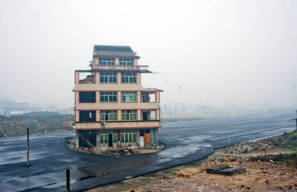 A half-demolished residential building stands alone in the middle of a vast construction site near a railway station in Wenling city of East China's Zhejiang province on Nov 21, 2012. Road house shows change in demolition dynamics