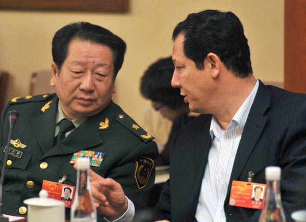 Akbar Wupper (right), administrative commissioner of Kashgar prefecture, the Xinjiang Uygur autonomous region, talks with Hou Xiaoqin, political commissar of the Xinjiang Armed Police Regiment, at a group discussion of deputies from Xinjiang to the National People’s Congress in Beijing on Tuesday. CUI JIA / CHINA DAILY Xinjiang's stability important for nation
