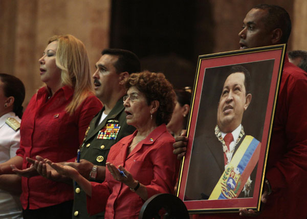 A Venezuelan man holds a picture of Venezuela's President Hugo Chavez during a mass to pray for his recovery at a church in Havana January 12, 2013. Chavez state 'favorable,' infection controlled