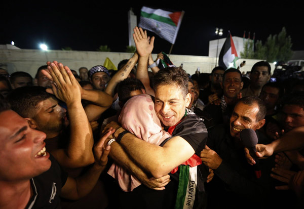 A freed Palestinian prisoner hugs a relative after his arrival in the West Bank city of Ramallah August 14, 2013. Israelis, Palestinians kick off peace talks
