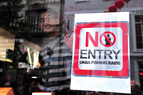 A poster is placed in a shop window during a protest against raids by the United Kingdom Borders Agency in Chinatown in central London on Tuesday. CARL COURT / Agence France-Presse Chinese protest UK 'fishing' raids